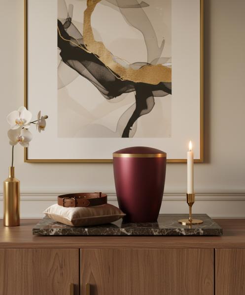Elegant burgundy pet urn with gold band, surrounded by luxury. A dignified, stylish keepsake for your beloved darling. A special place of remembrance – discover in our shop now.